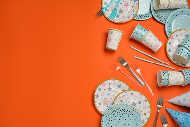 Photo of Disposable tableware on orange background, flat lay. Space for text