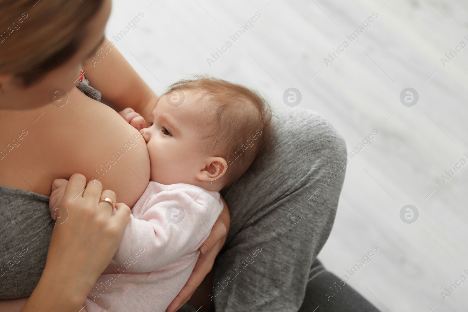 Photo of Young woman breastfeeding her baby at home, closeup