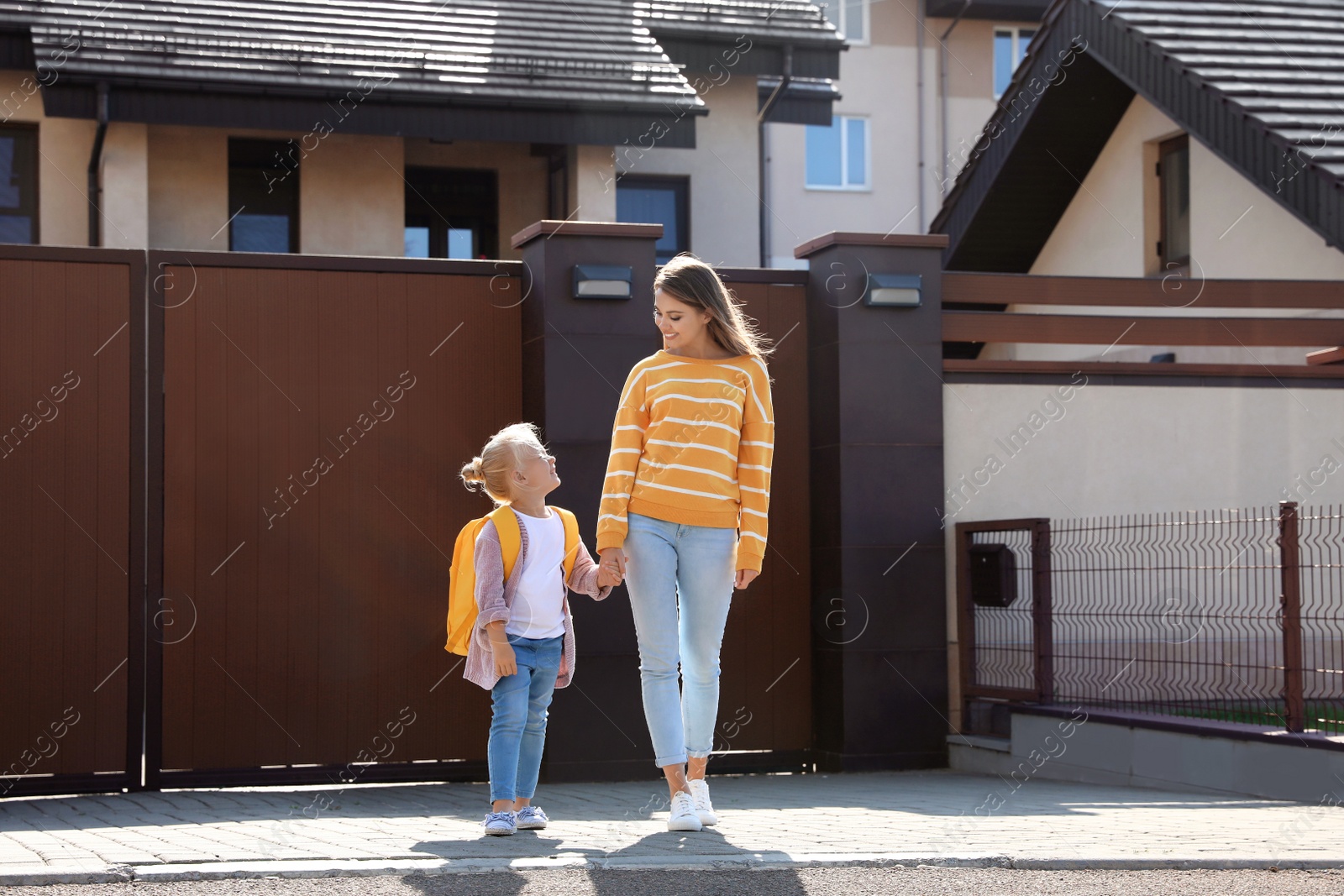 Photo of Young mother taking her little child to school on street