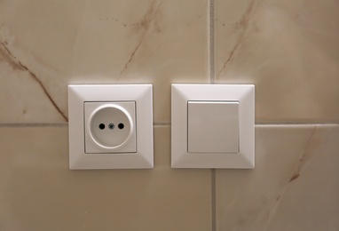 Photo of Electric socket and light switch on wall