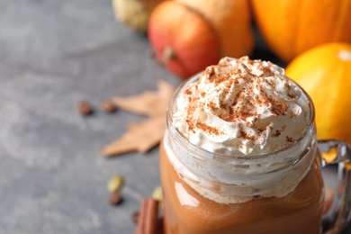 Photo of Mason jar with tasty pumpkin spice latte on gray table, closeup with space for text