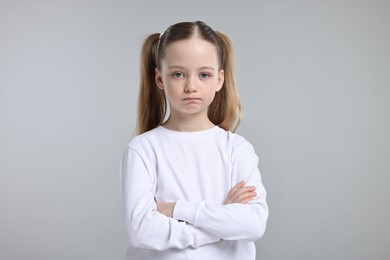 Photo of Portrait of sad girl with crossed arms on light grey background