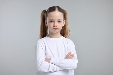 Portrait of sad girl with crossed arms on light grey background