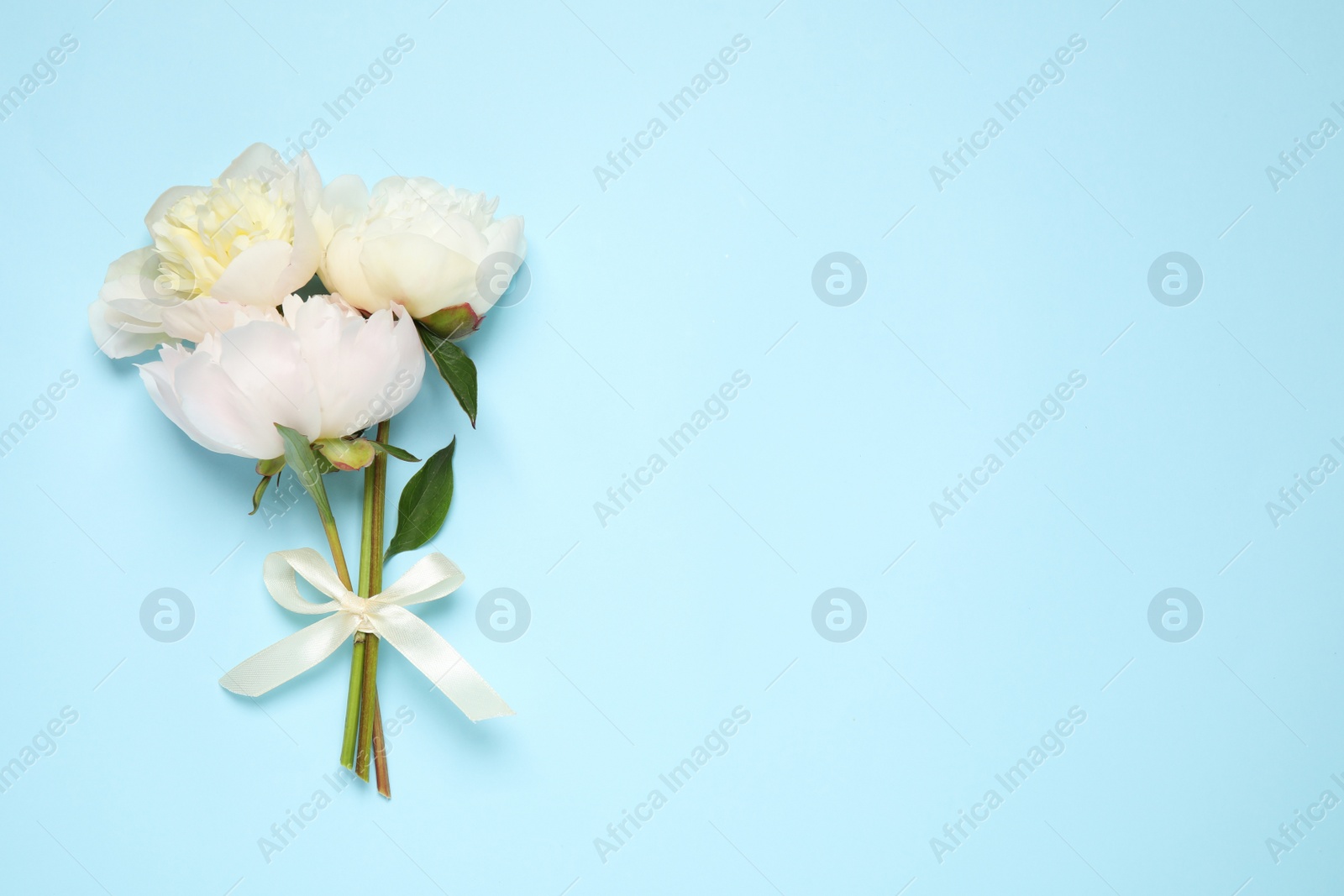 Photo of Beautiful bouquet of fresh peonies on light blue background, flat lay. Space for text