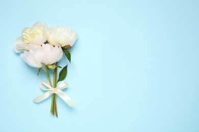 Photo of Beautiful bouquet of fresh peonies on light blue background, flat lay. Space for text