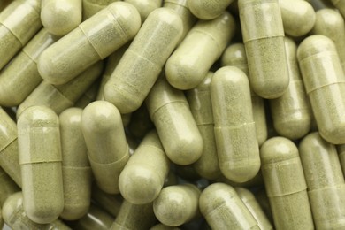 Photo of Light green vitamin capsules as background, top view