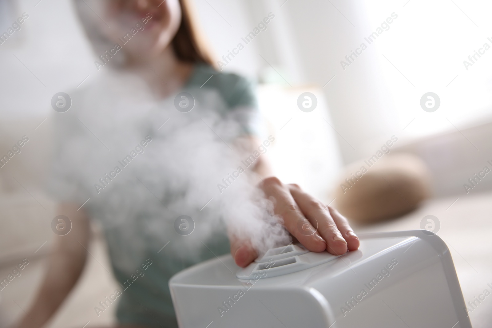 Photo of Woman using modern air humidifier at home, closeup