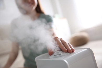 Woman using modern air humidifier at home, closeup