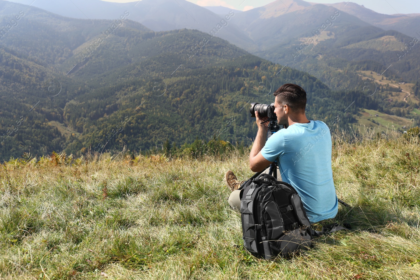 Photo of Photographer with backpack, camera and tripod surrounded by breathtakingly beautiful nature