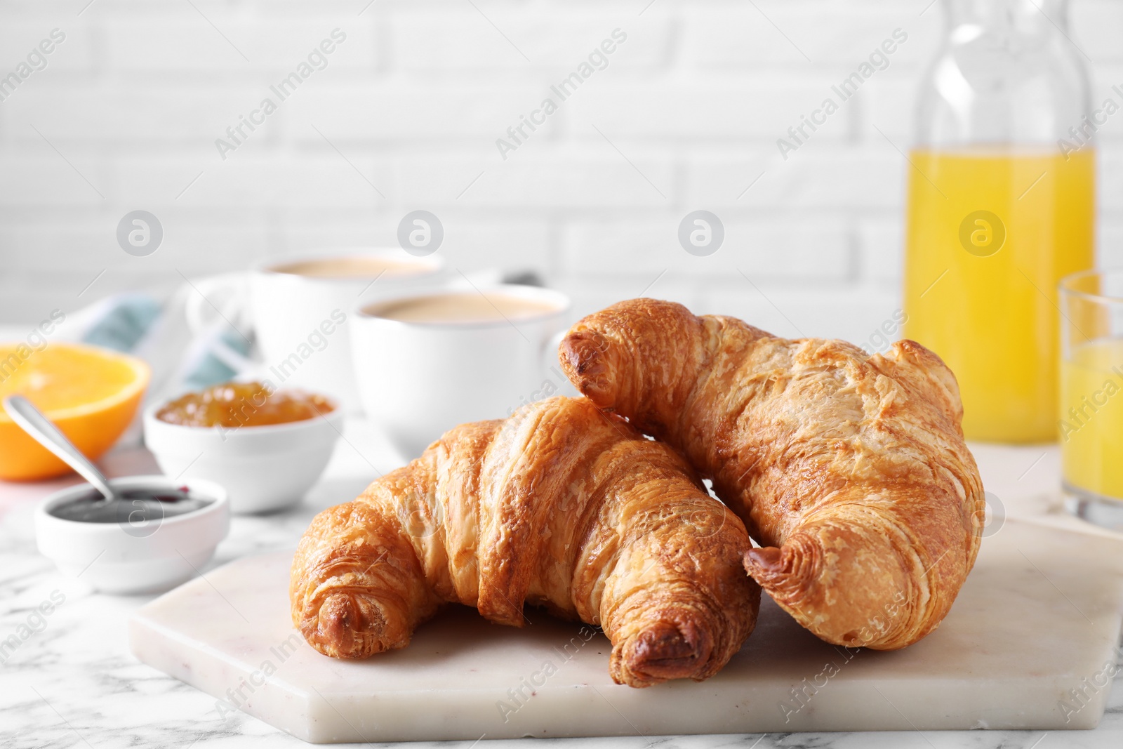 Photo of Tasty breakfast. Fresh croissants and jam on white marble table