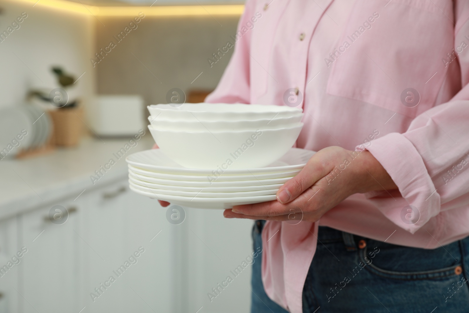 Photo of Woman holding plates in kitchen, closeup view