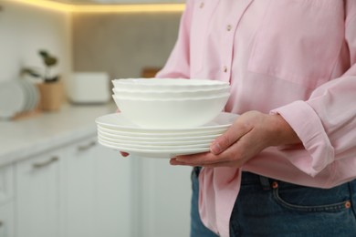 Woman holding plates in kitchen, closeup view