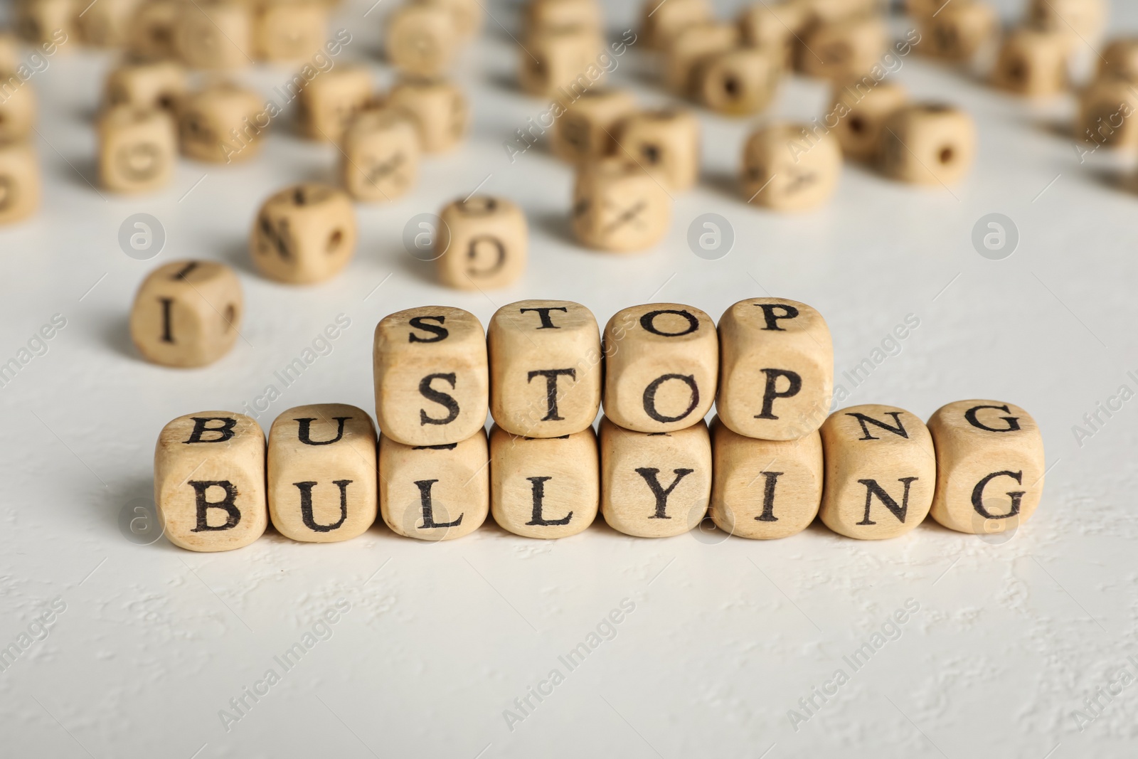 Photo of Phrase Stop Bullying made of wooden cubes with letters on stone surface, closeup