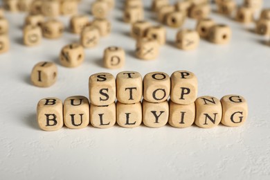 Photo of Phrase Stop Bullying made of wooden cubes with letters on stone surface, closeup