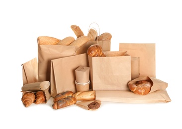 Different fresh bakery products in paper bags on white background