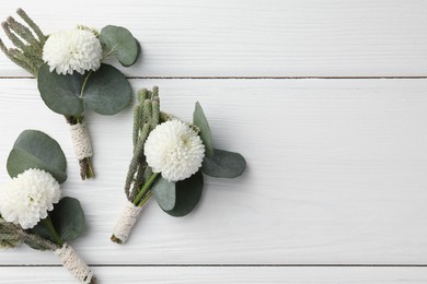Photo of Small stylish boutonnieres on white wooden table, flat lay. Space for text