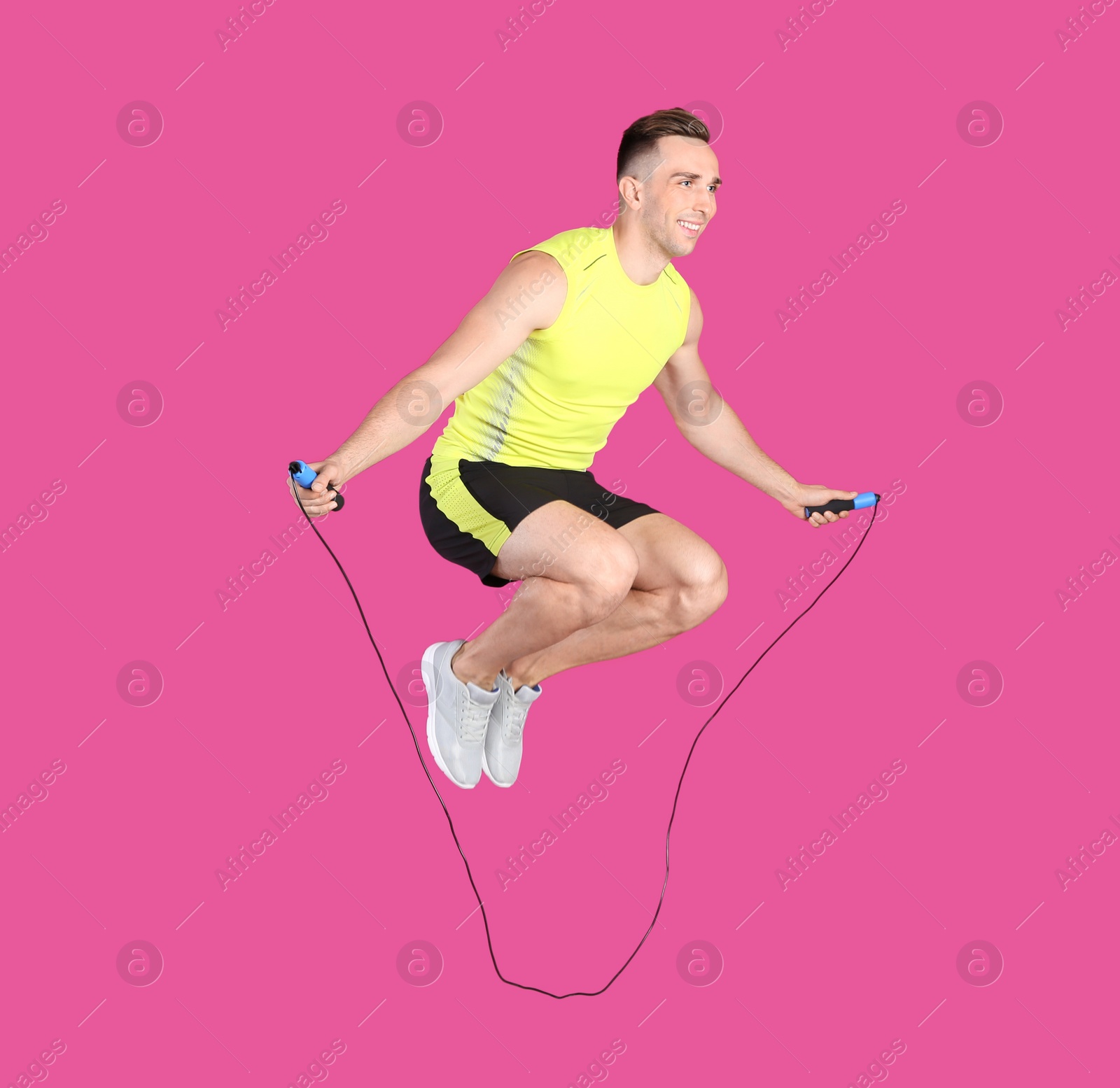 Photo of Full length portrait of young sportive man training with jump rope on color background