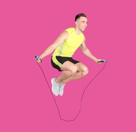 Photo of Full length portrait of young sportive man training with jump rope on color background