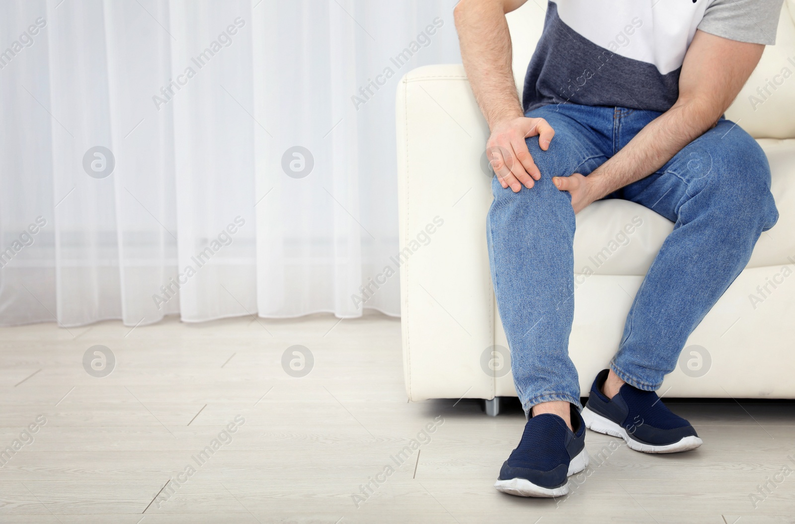 Photo of Young man suffering from leg pain indoors, closeup. Space for text