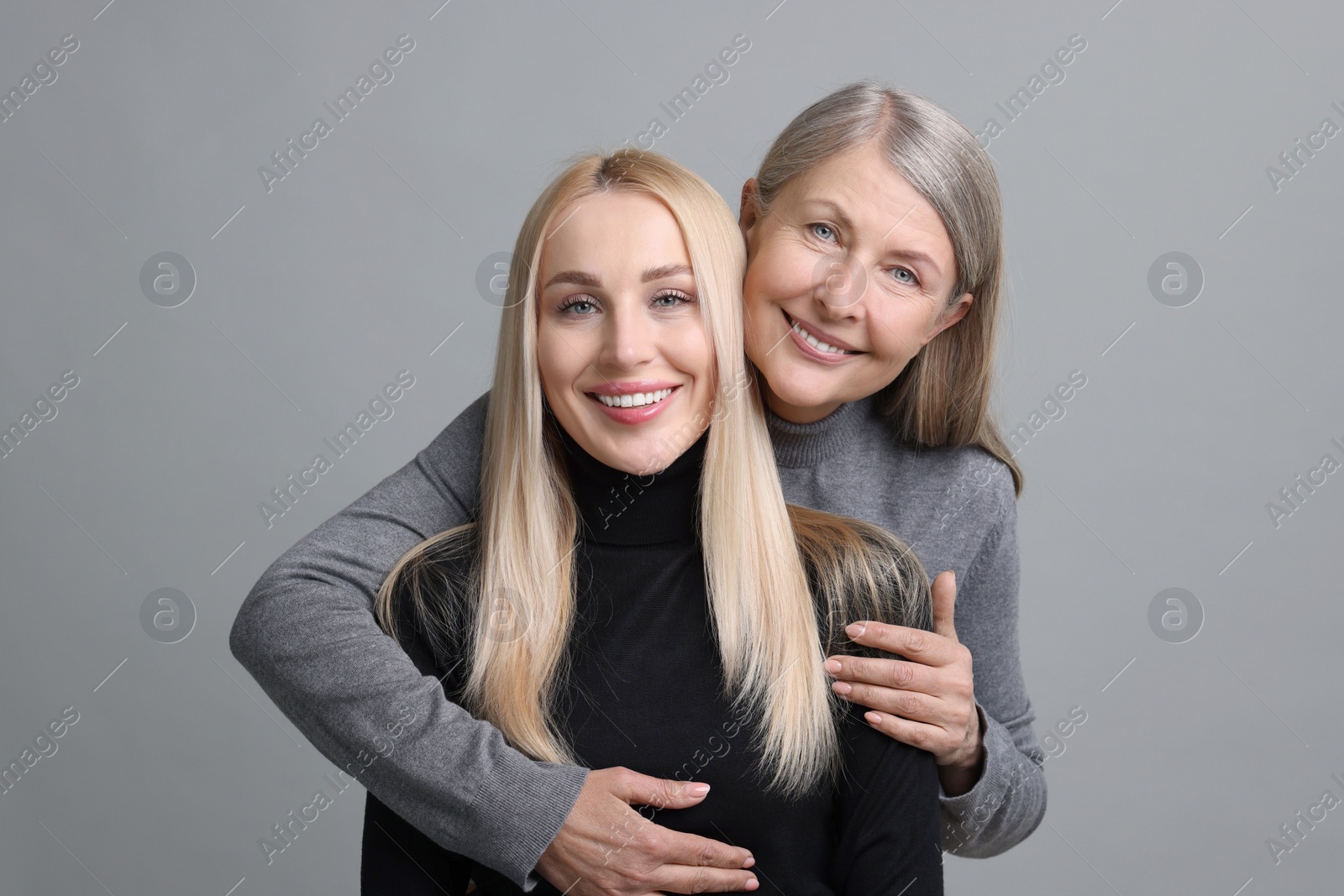 Photo of Family portrait of young woman and her mother on grey background