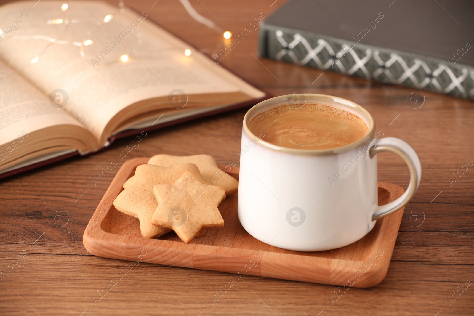 Photo of Cup of delicious coffee and star shaped cookies on wooden table