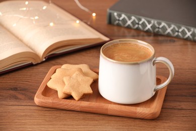 Photo of Cup of delicious coffee and star shaped cookies on wooden table