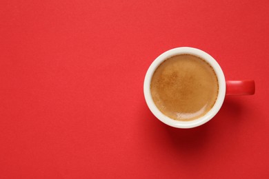 Photo of Cup of aromatic coffee on red background, top view. Space for text