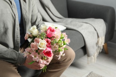 Man holding bouquet of beautiful flowers indoors, closeup