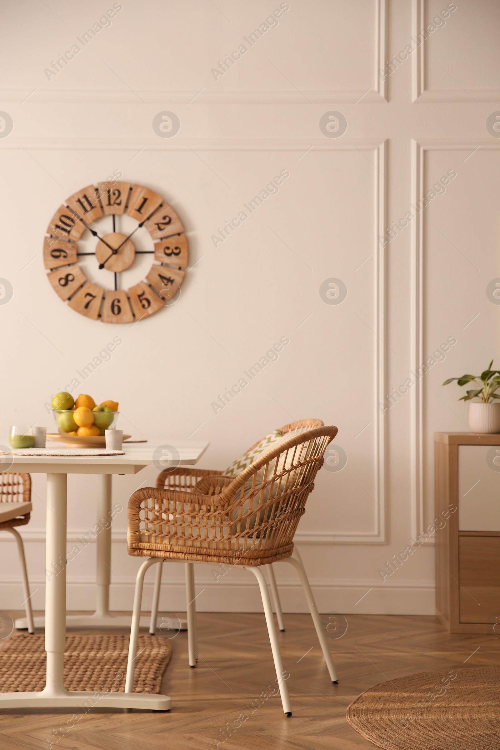 Photo of Stylish white dining table and wicker chairs in room. Interior design