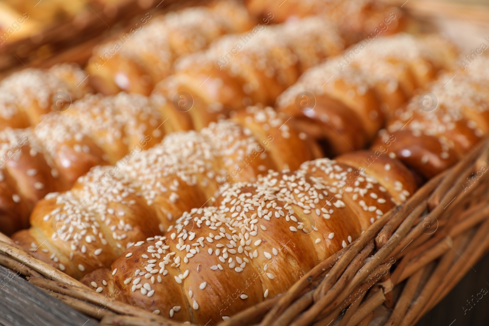 Photo of Wicker tray with tasty fresh buns, closeup. Bakery products