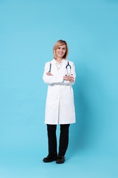 Photo of Smiling doctor with crossed arms on light blue background