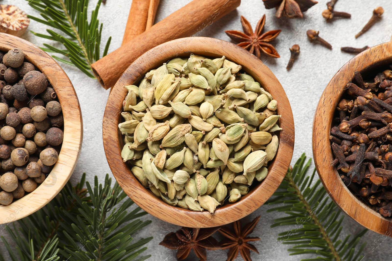 Photo of Different aromatic spices and fir branches on light textured table, flat lay