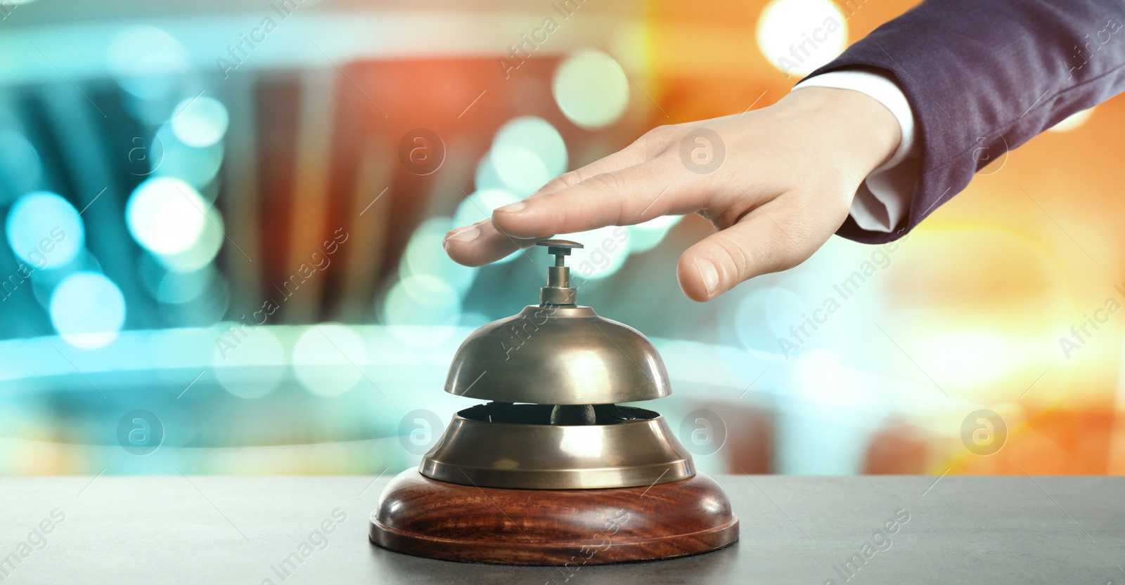 Image of Man ringing hotel service bell on blurred background, closeup. Banner design