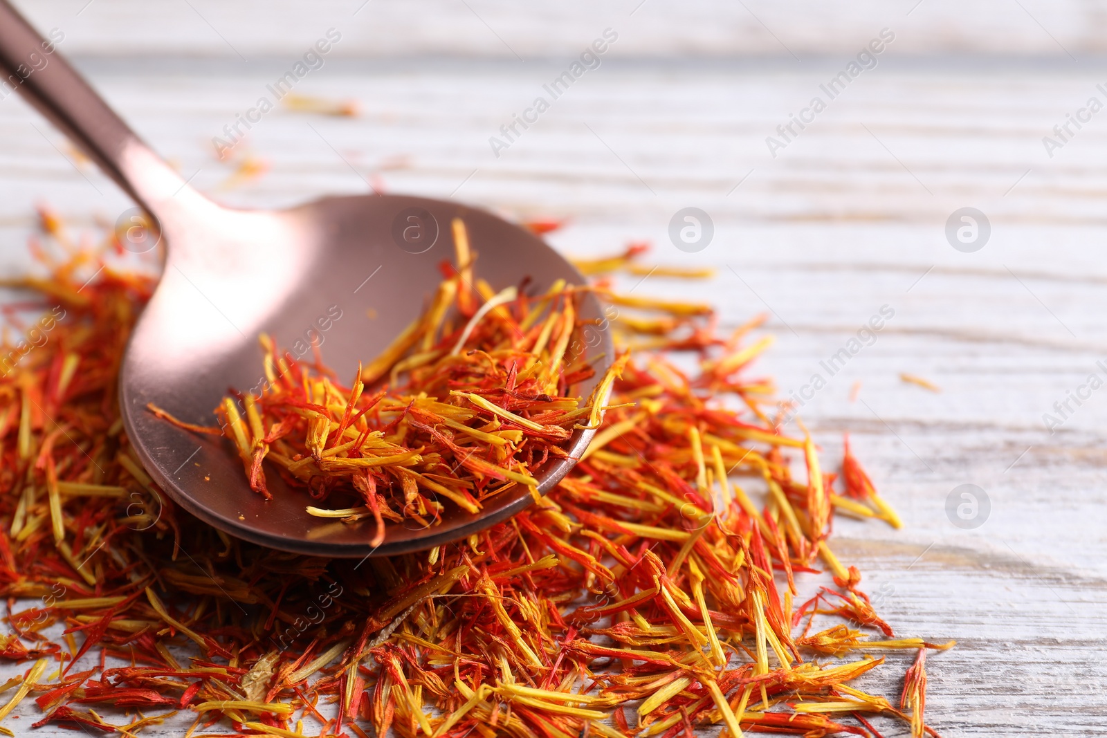 Photo of Aromatic saffron and spoon on wooden table, closeup