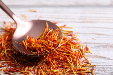 Aromatic saffron and spoon on wooden table, closeup