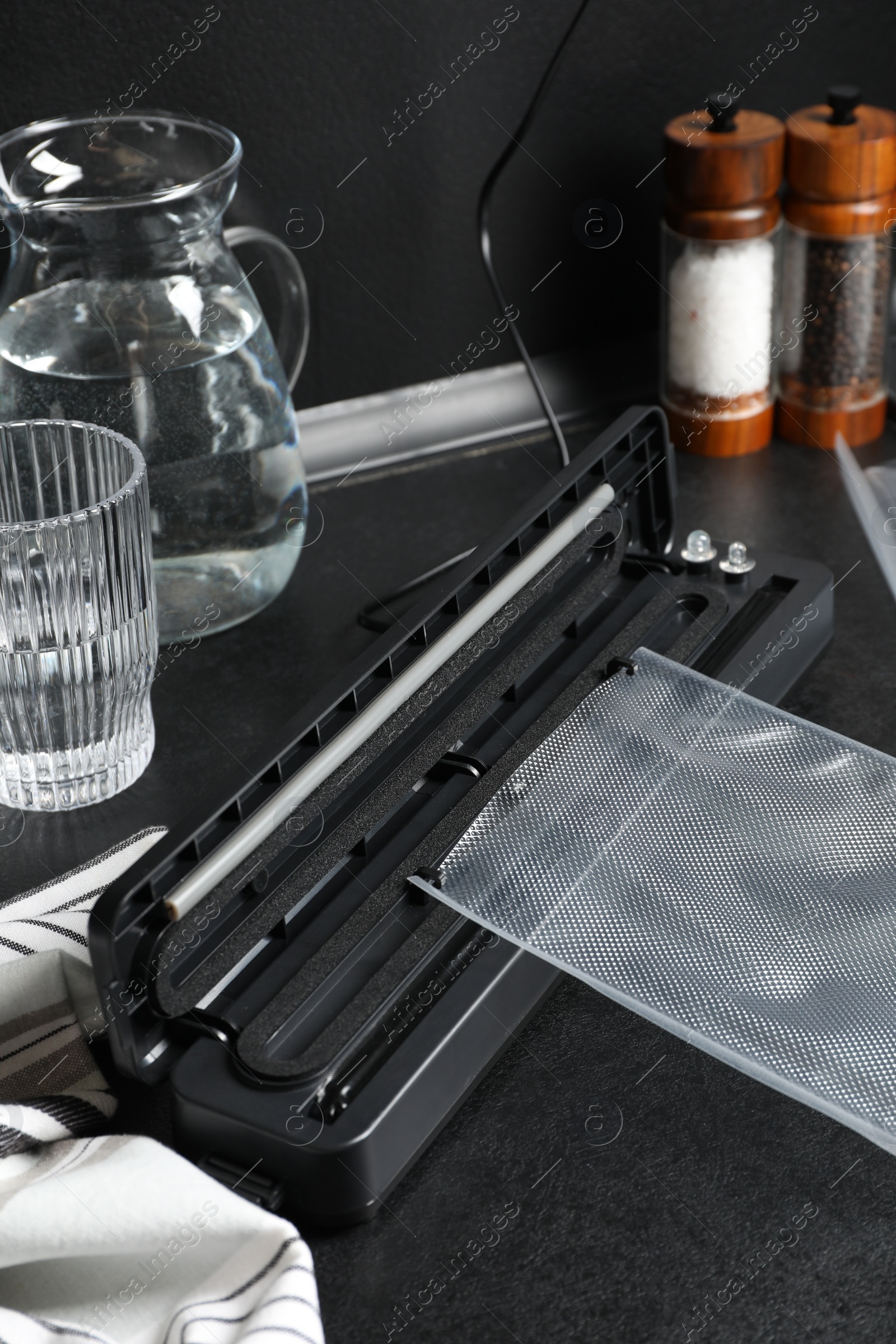 Photo of Sealer for vacuum packing with plastic bag on black kitchen countertop