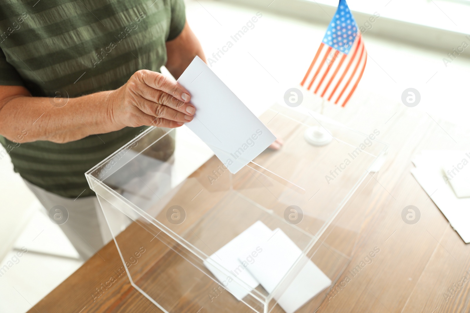 Photo of Elderly woman putting ballot paper into box at polling station, closeup