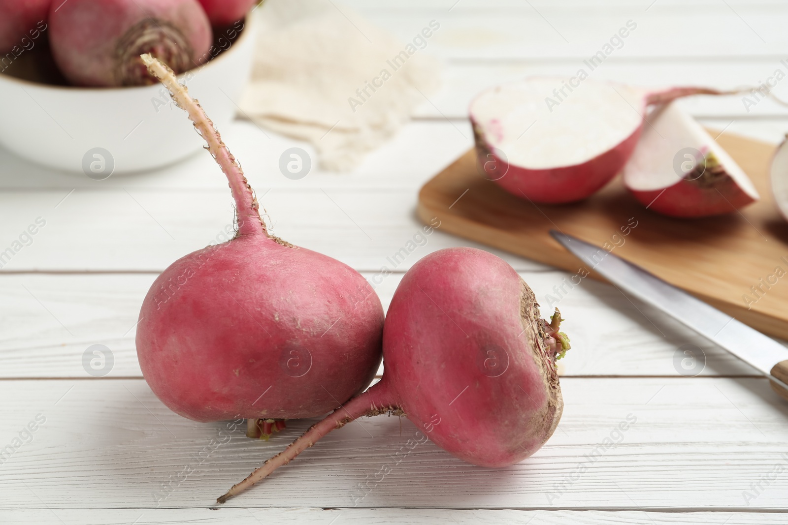 Photo of Raw red turnips on white wooden table, closeup