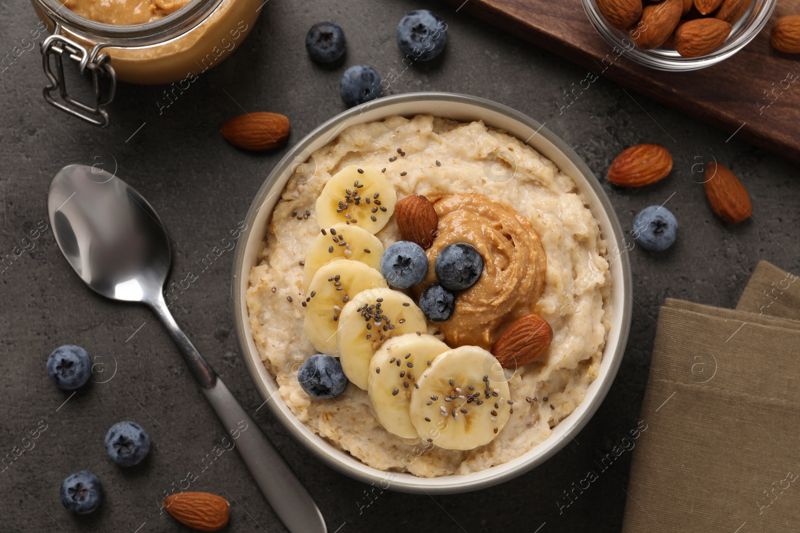 Photo of Tasty oatmeal porridge with toppings served on grey table, flat lay