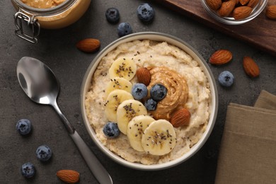 Photo of Tasty oatmeal porridge with toppings served on grey table, flat lay