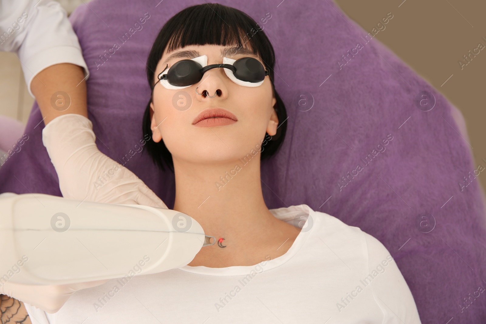 Photo of Young woman undergoing laser tattoo removal procedure in salon, above view