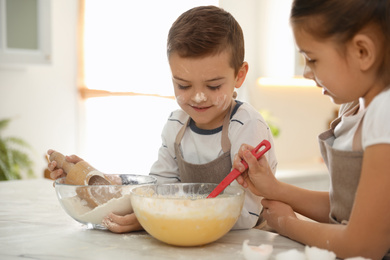 Photo of Cute little children cooking dough together in kitchen