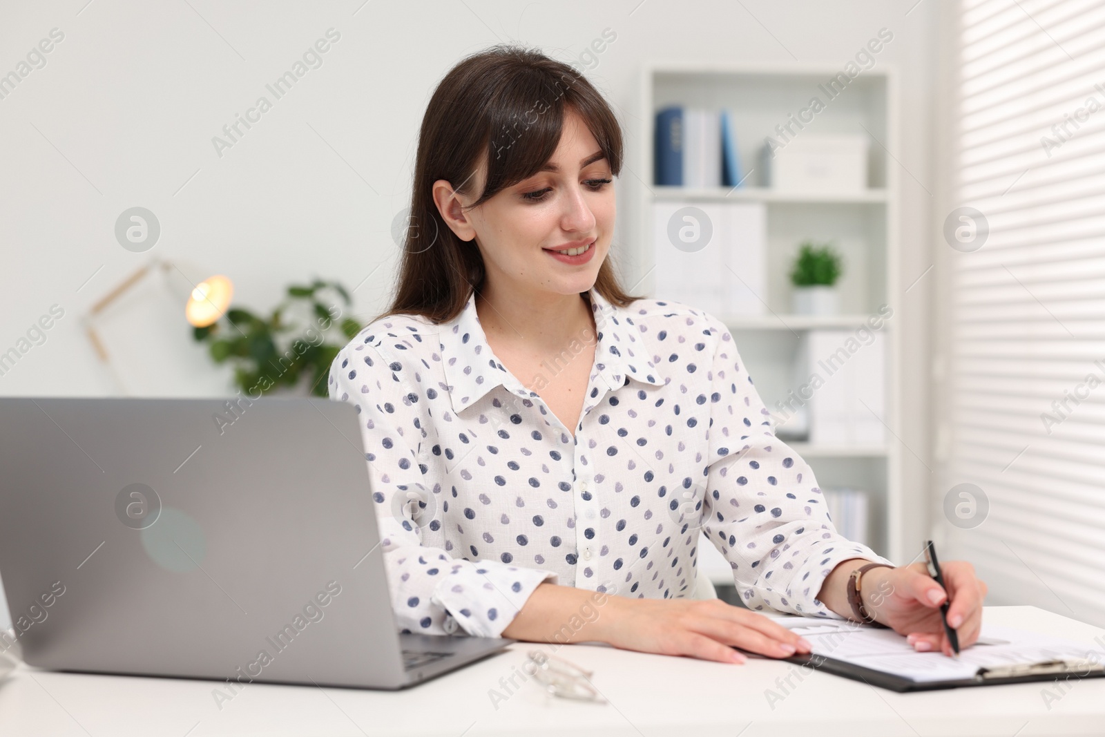 Photo of Smiling secretary working at table in office