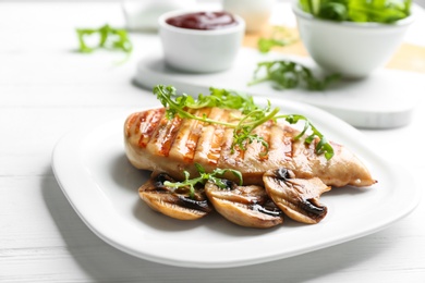 Photo of Tasty grilled chicken fillet with mushrooms and arugula on white table, closeup