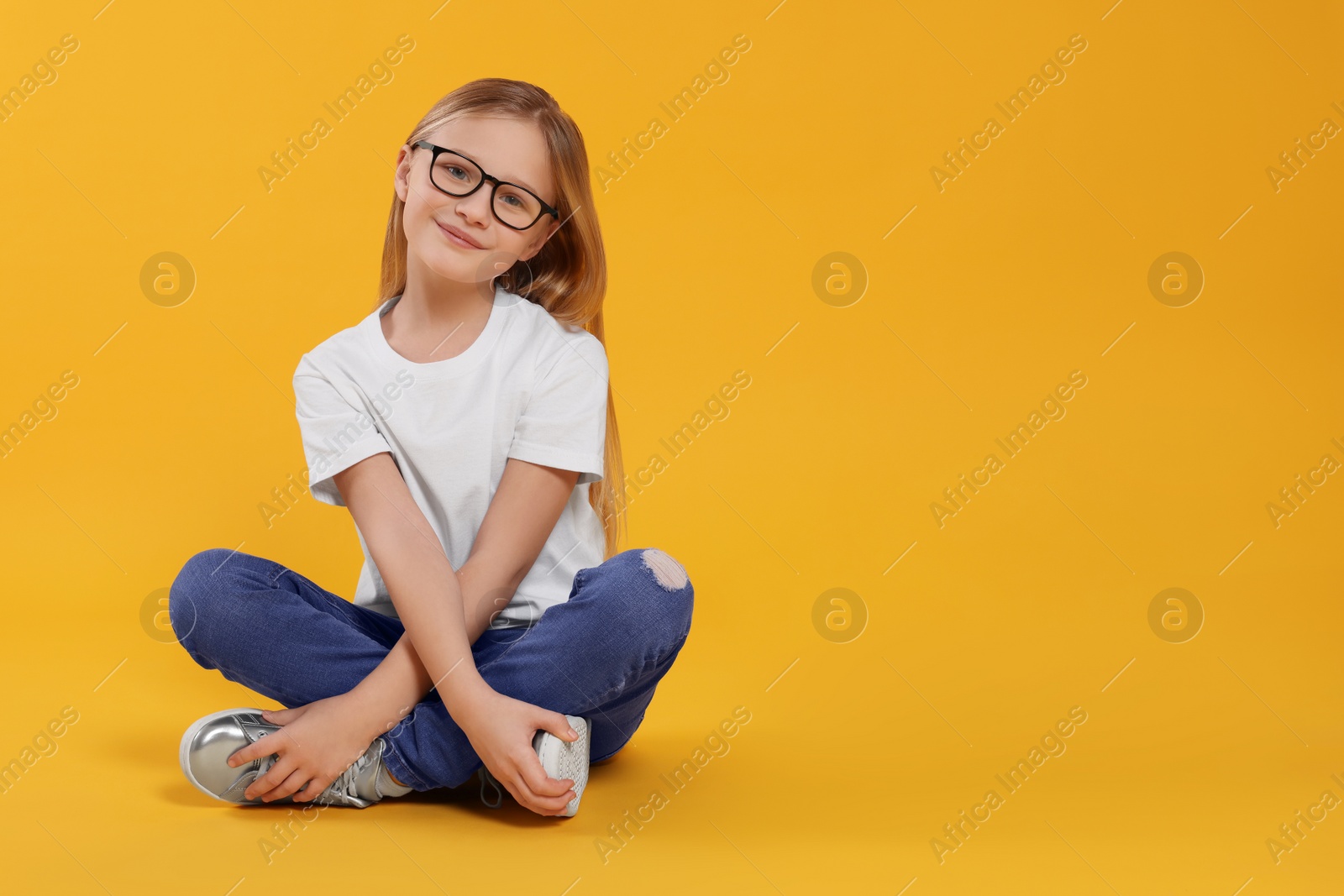 Photo of Cute girl in glasses on orange background. Space for text