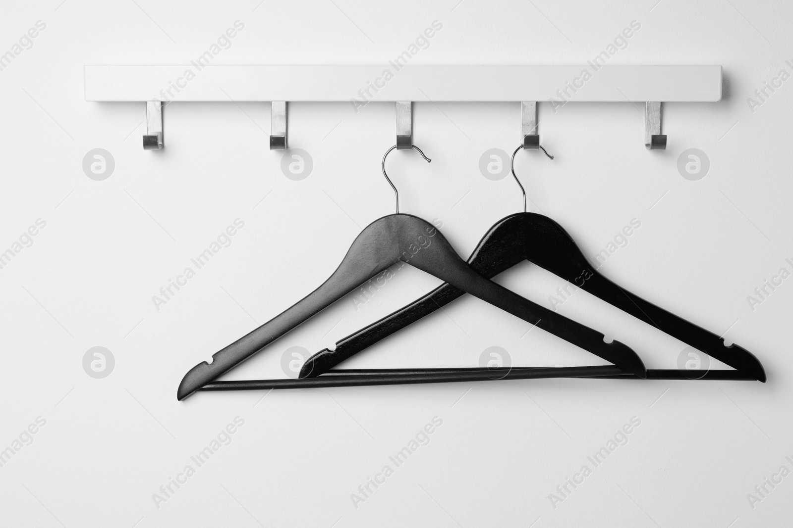 Photo of Rack with empty black clothes hanger on white wall