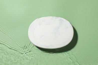 Photo of Presentation for product. Marble podium in water on green background, top view