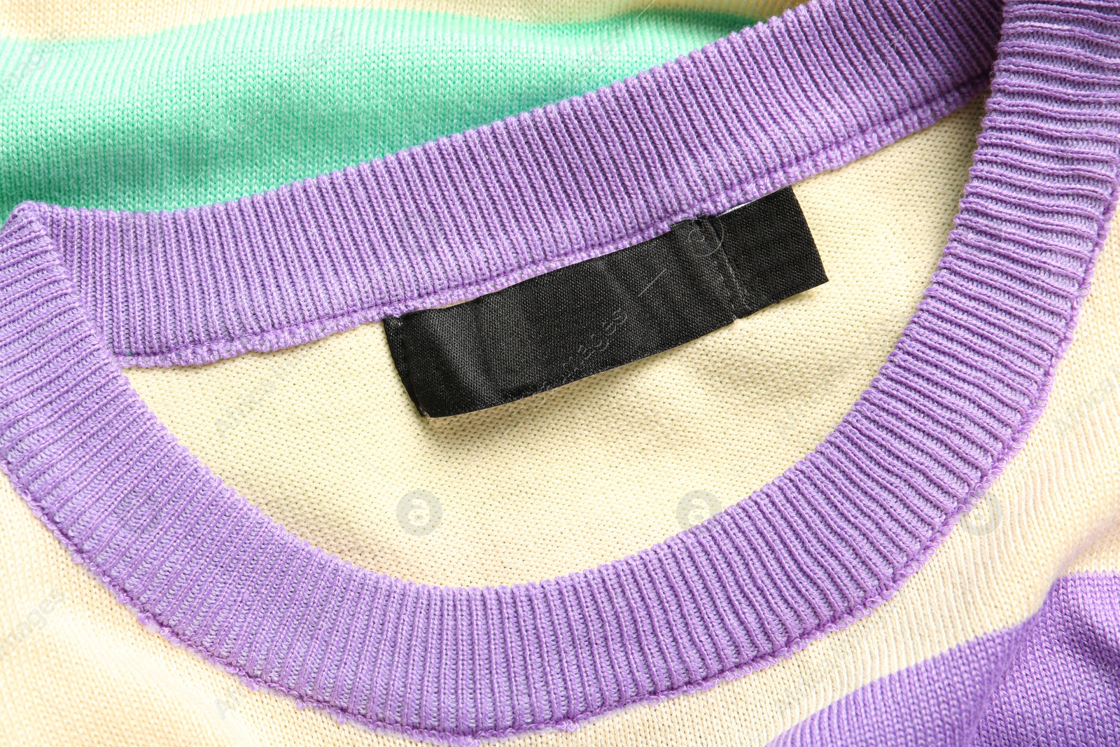 Photo of Blank clothing label on stylish sweater, closeup