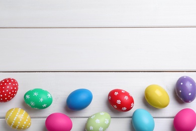 Photo of Colorful eggs on white wooden background, flat lay with space for text. Happy Easter