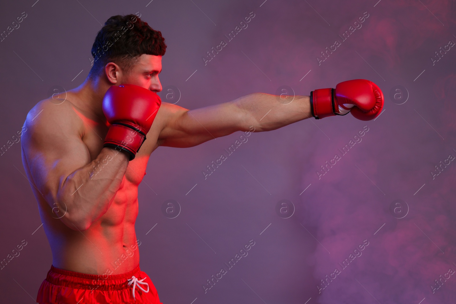 Photo of Man in boxing gloves fighting on color background. Space for text